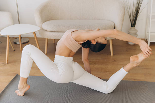 istock Young woman practicing yoga king pigeon pose at home 2206677083