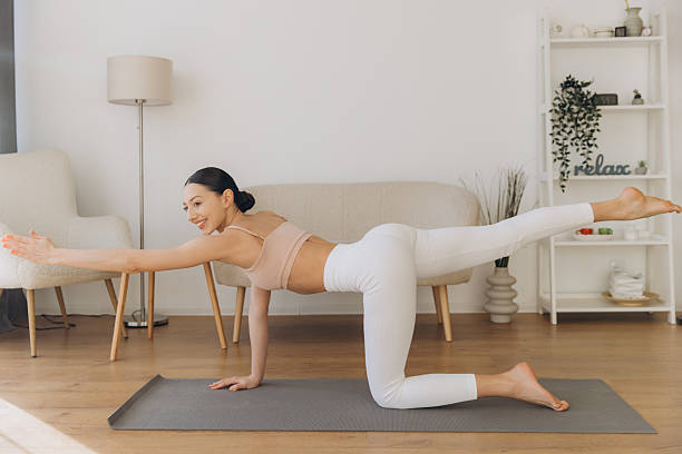 istock Young woman practicing yoga bird dog pose at home 2206677108