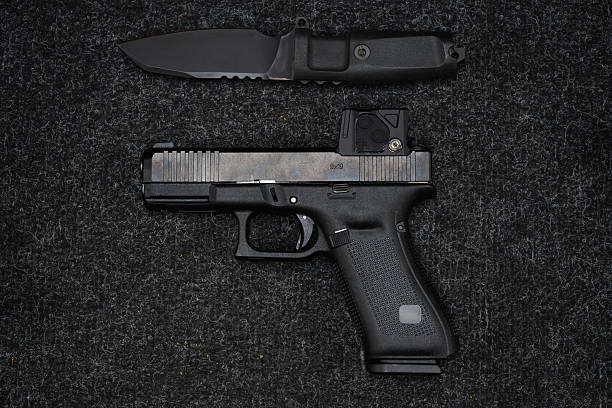 istock Modern tactical 9mm pistol with a collimator sight and a sharp knife. 2206677960
