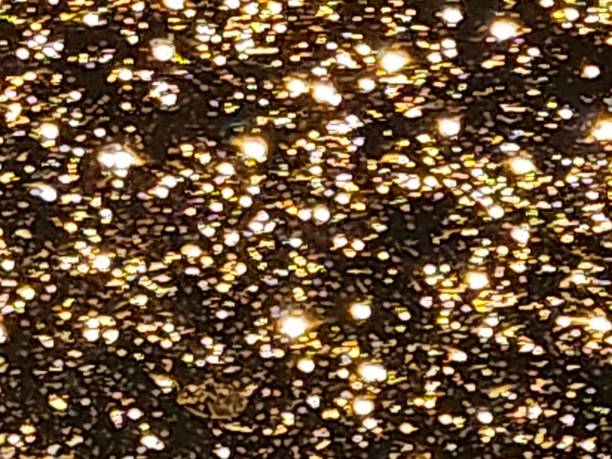 Raindrops slide down the glass at night, reflecting urban lights. The diffuse glow turns each drop into a tiny shimmering universe, where golden and bluish tones create a mesmerizing effect against the surrounding darkness.