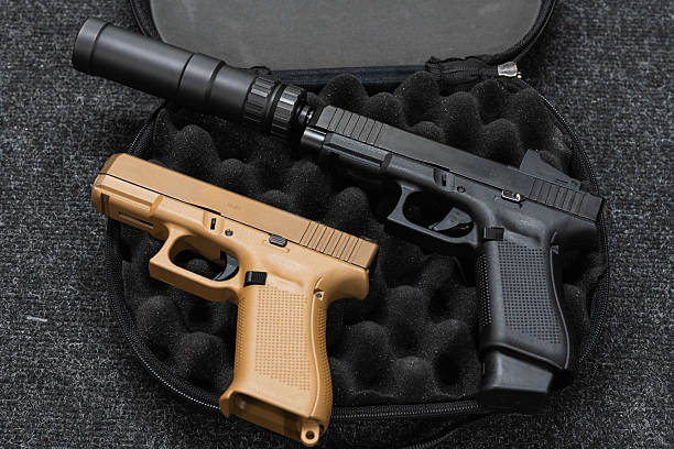 istock Tactical firearms, two pistols, sand colored and black with silencer and red dot sight. 2206678415