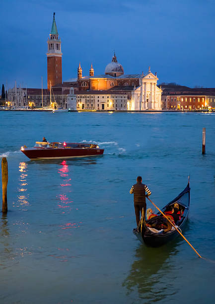 Venice, Italy - 14 March 2025 - The city on the sea, with the most characteristic places and touristic attractions in the world, during blue hour and night. Here in particular: the view of San Giorgio church with gondolas.