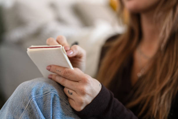 istock Young woman writing notes while sitting comfortably indoors 2206681398