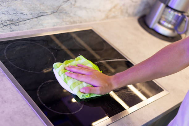 istock Person Cleaning a Kitchen Stovetop Surface With a Cloth 2206682759