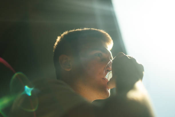 Man Drinking Water in Bright Sunlight With Lens Flares and Shadows