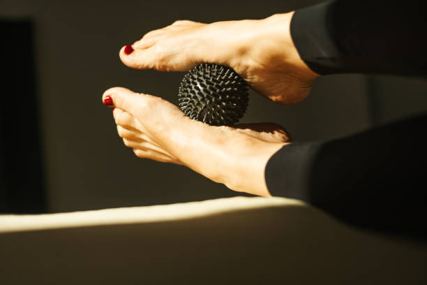 Close-up of feet using a spiked massage ball in a therapy session, emphasizing relaxation and health.