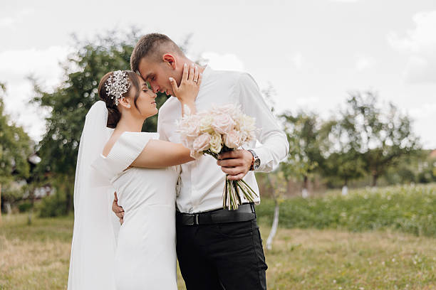 istock A bride and groom are standing in a field, holding hands 2206686657