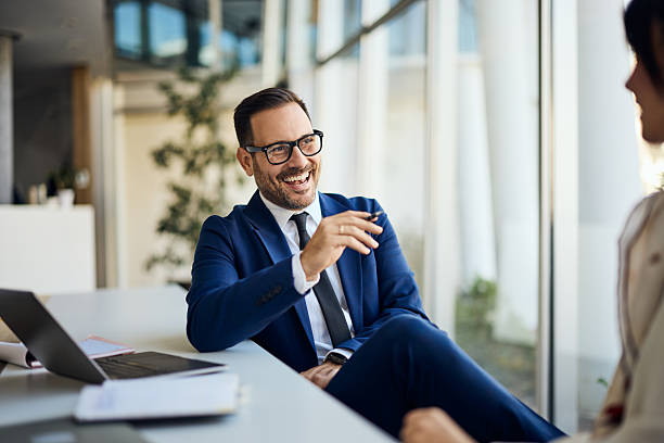 istock Smiling Businessman Talking to Colleague in Modern Office Setting 2206687036
