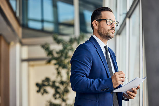 istock Confident Businessman in Formal Attire Making Notes While Looking Out a Window 2206687057