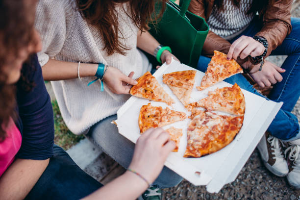 istock friends eating pizza outdoors 2206688811