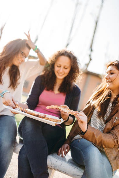 istock friends eating pizza outdoors 2206689027