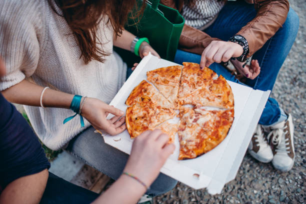 istock friends eating pizza outdoors 2206689107