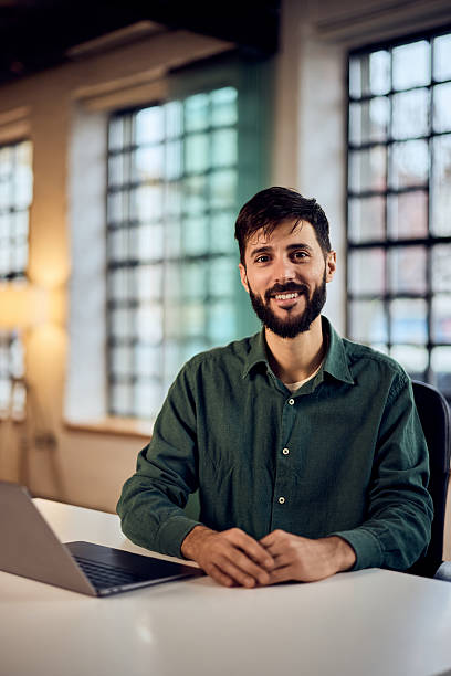 istock Smiling Professional Man Sitting at Desk in Modern Office Environment 2206689466