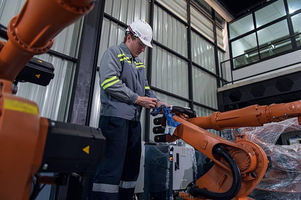 istock Engineer standing by robotic arm and operating machine in industry factory, technician worker check for repair maintenance electronic operation 2206690817