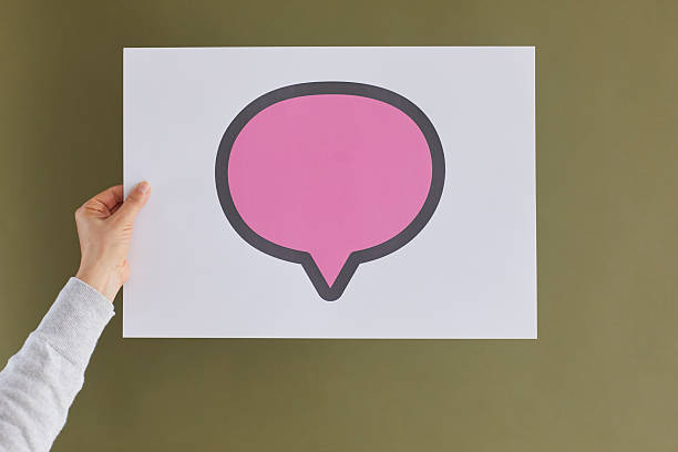 Person hand hold paper banner with speech bubble for advertising or sale deal. Woman demonstrate placard isolated on green studio background. Empty copy space, mockup. Discount and promotion.