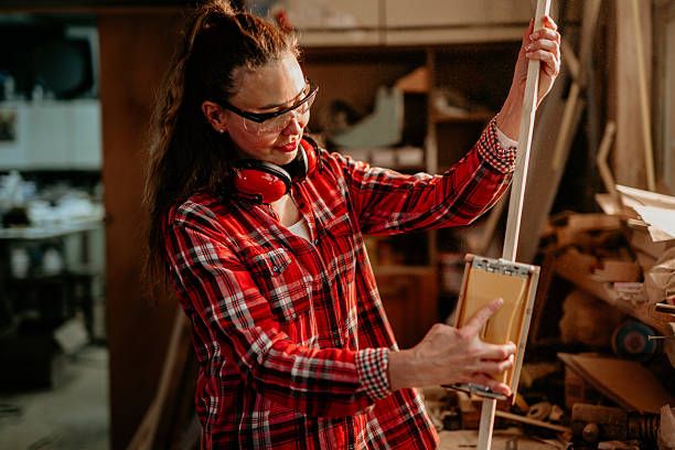 istock Female carpenter sanding wooden plank in workshop 2206693110