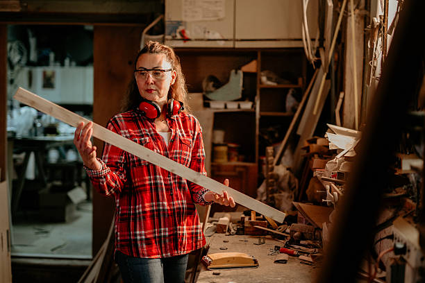 istock Female carpenter examining wooden plank in workshop 2206693113