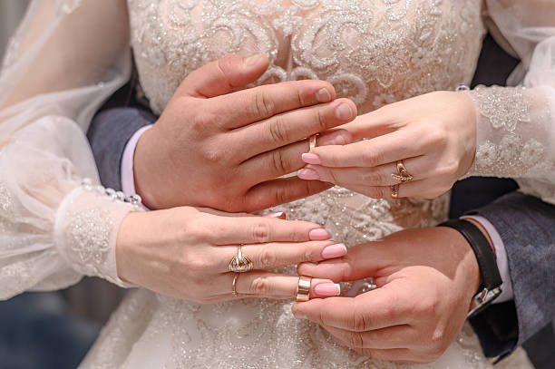 istock Groom embracing bride as they exchange with her wedding rings 2206693187