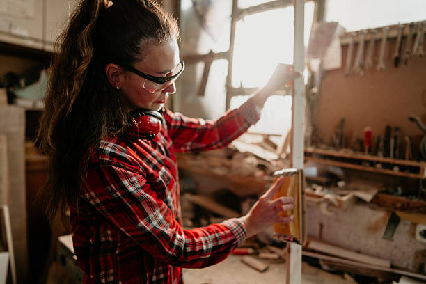 istock Carpenter woman sanding wooden plank in workshop 2206693206