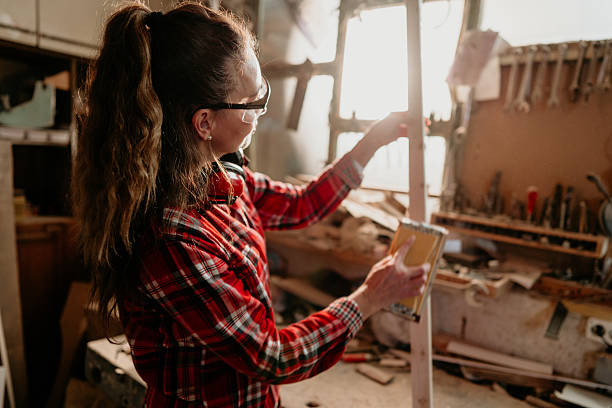 istock Carpenter woman sanding wood in workshop using sandpaper 2206693207