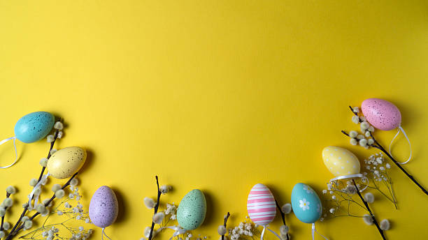 istock Willow branches and Easter eggs are laid out on a yellow background. Yellow Flat lay background. 2206693519