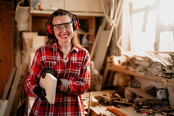 istock Female carpenter smiling and holding wood plank in workshop 2206693784
