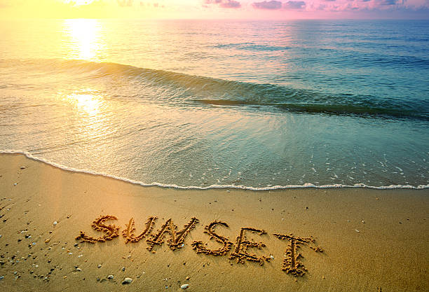 istock Seascape in the evening with a wave and word Sunset. Sandy beach during sunset 2206694989