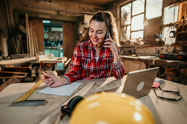 istock Carpenter woman working and talking on phone in workshop 2206695270