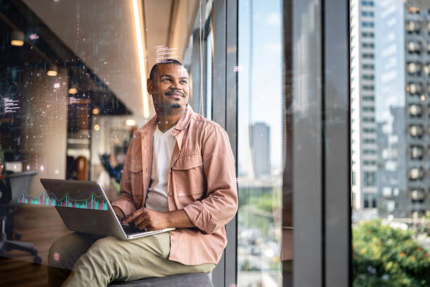 istock Smiling man working on a laptop in a modern office with a city view and digital data overlay 2206698704