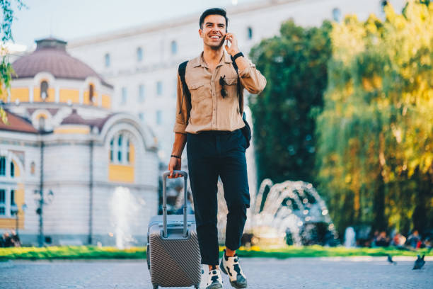 istock Tourist with suitcase is talking on the phone 2206699016