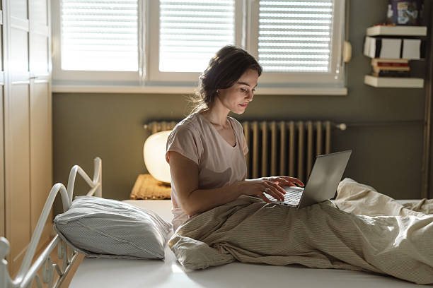 istock Young woman using a laptop while sitting in bed during the morning 2206699163