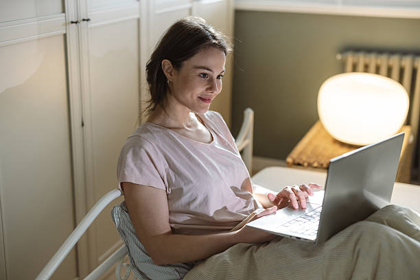 istock Woman using a laptop while relaxing comfortably at home in the evening 2206699190