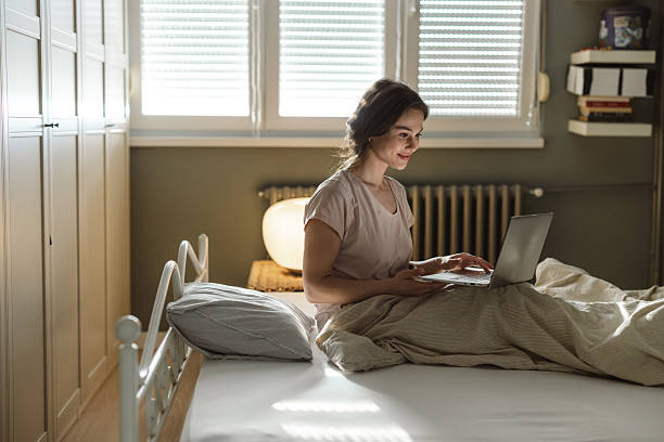 istock Young woman using a laptop while sitting in bed during the morning 2206699946