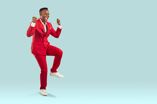 Happy excited Afro American man in red suit celebrating victory on copy space background stock photo