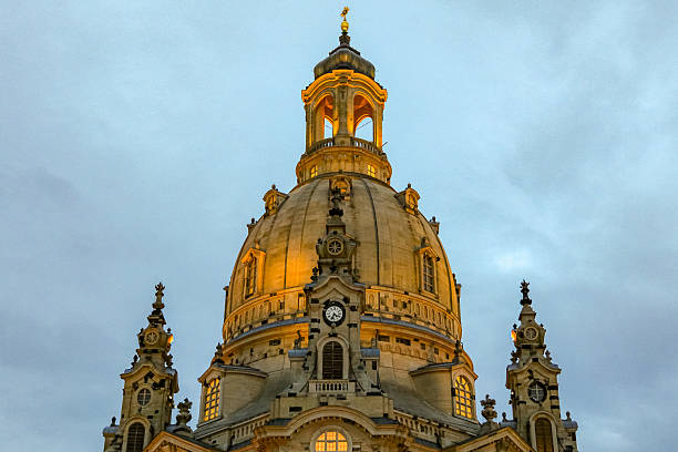 A large building Frauenkirche in Dresden Germany with a clock on the front. The clock is set at 10:00. The building is lit up at night
