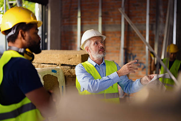 istock Construction Workers Reviewing Plans on a Building Site Wearing High-Visibility Gear 2206703106