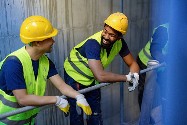 Construction Workers Smiling and Chatting on Job Site Wearing Safety Gear