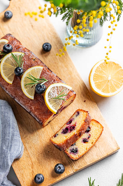 Lemon pie with sugar glaze, blueberries, decorated with rosemary and citrus slices on a wooden board
