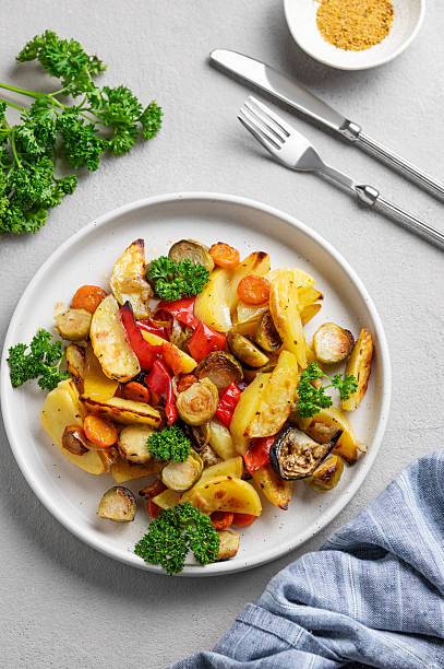 istock Baked vegetables potatoes, cabbage, pepper and onion in a plate on a light background with fresh parsley. 2206703748