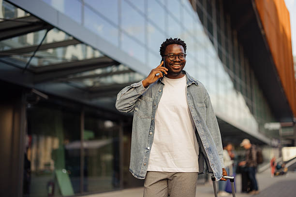 istock Man Talking On Phone With Luggage Outside Modern Building 2206705300