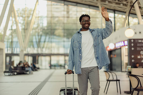 istock Traveler Waving Goodbye in Modern Transportation Hub While Holding Luggage 2206705328