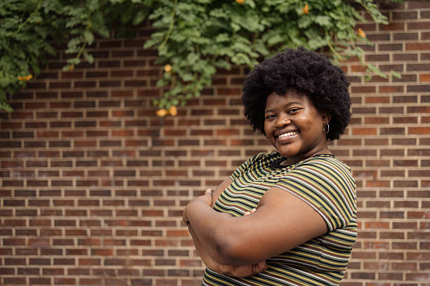 istock Smiling Woman Posing Against Brick Wall with Greenery in the Background 2206705723