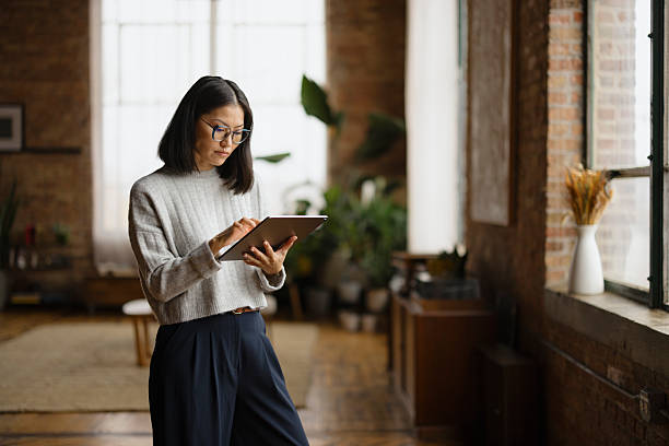 istock Focused Woman Using a Digital Tablet in a Cozy Brick Apartment 2206706351