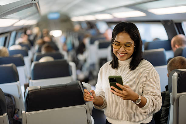 istock Young Woman Smiling While Using Smartphone on a Busy Modern Train 2206706418