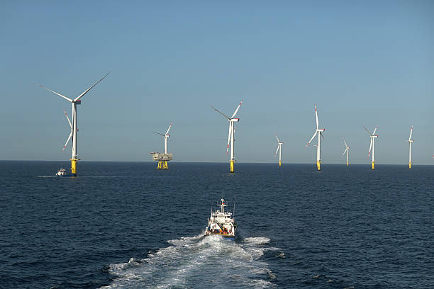 istock Offshore wind farm service: Passenger transporting ship front of big Offshore Wind farm and wind turbines. Blue wavy sea and moody, dramatic sky. 2206707189