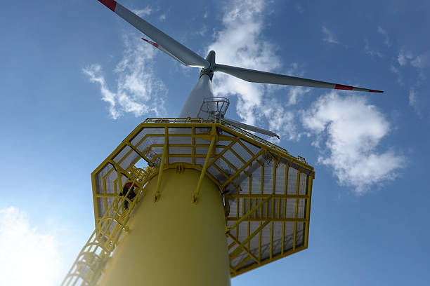 istock High-Risk offshore Wind Turbine Maintenance –Technician climbing on large Offshore wind turbine  - Blade Spinning Above. 2206707284