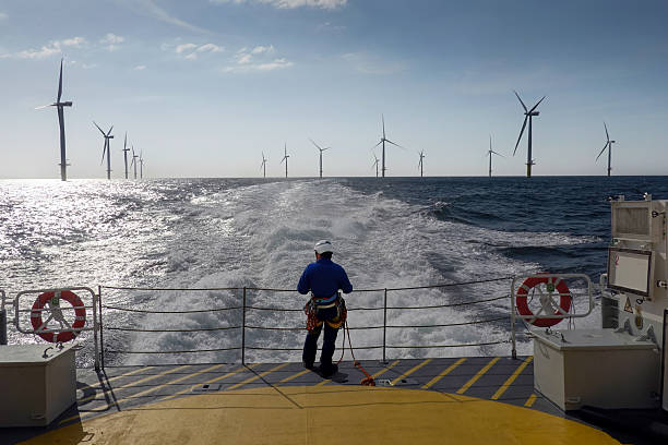 istock Rope Access Technician Overlooks Offshore Wind Farm – Dynamic Boat Wake 2206707328