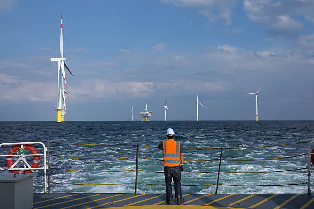 istock Offshore Technician Observing landing Helicopter and Wind_Farm from deck 2206707461