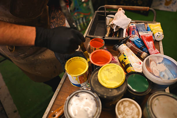 istock Artist picking up yellow paint from a can in his workshop 2206707547