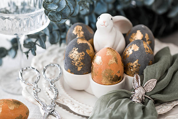 istock The banner. Table setting. A plate with a rabbit and a napkin, Easter eggs with gilding and a branch of eucalyptus on a linen tablecloth. The concept of a bright Easter holiday. 2206707952